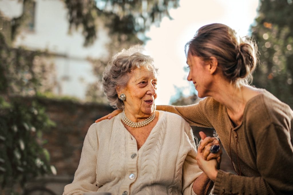 Alte Frau sieht jüngere Frau lächelnd erfreut an; Pflege